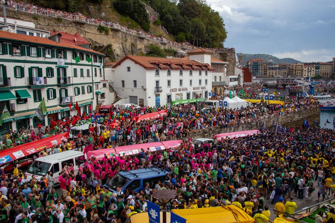 Niños asomados a la barandilla del paseo viendo pasar las traineras