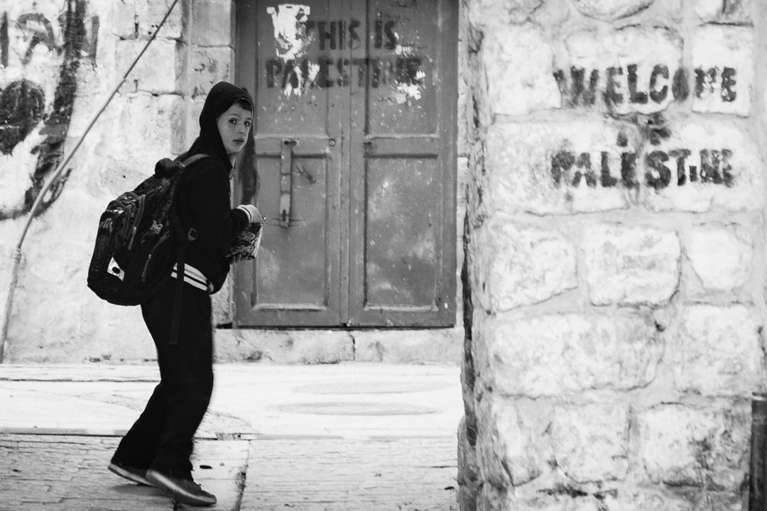 Mujer caminando con la compra en un barrio palestino